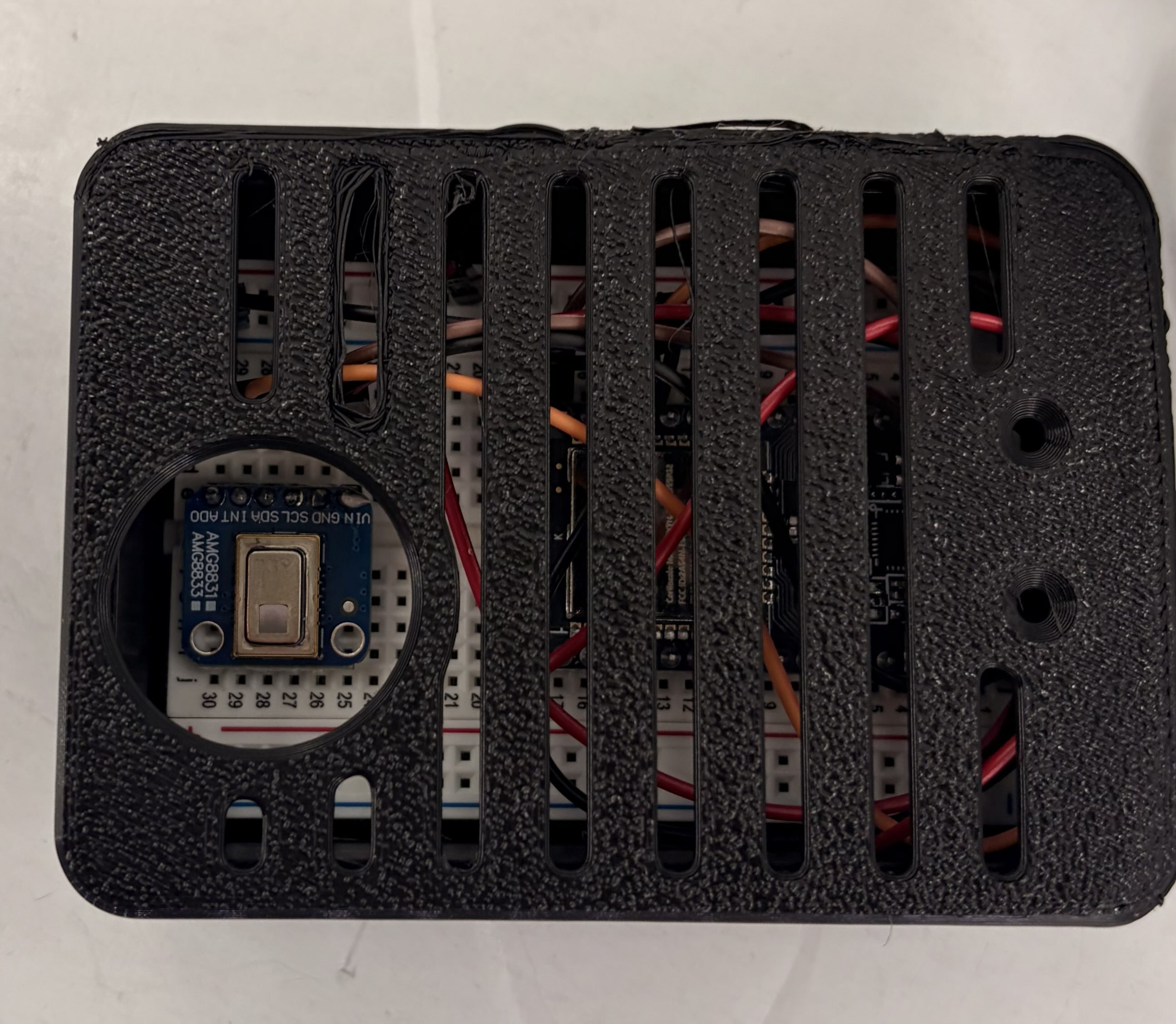 Sensor setup: AMG8833 thermal camera mounted above doorway, connected to ESP32 microcontroller, housed in 3D-printed enclosure.
